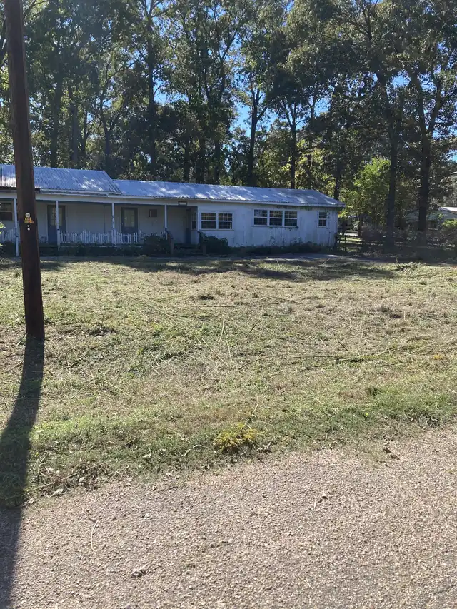 A rural lot cut down and cleared in front of a metal-roof house